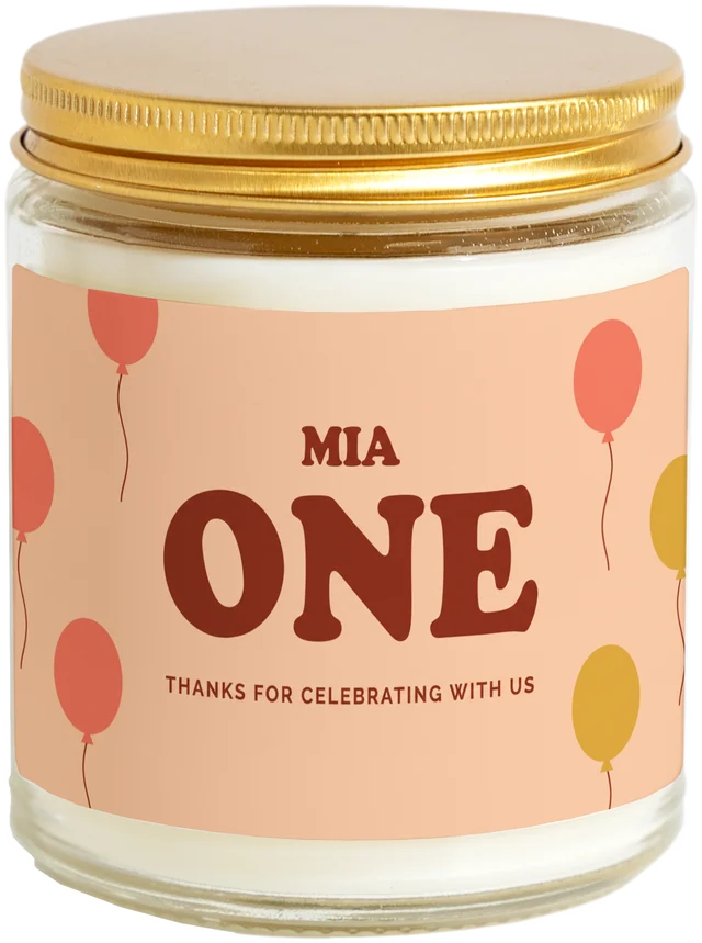 A 9 oz candle jar with a sample First birthday favors label