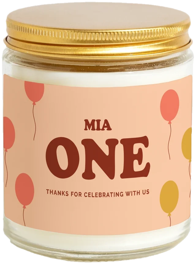 A 9 oz candle jar with a sample First birthday favors label