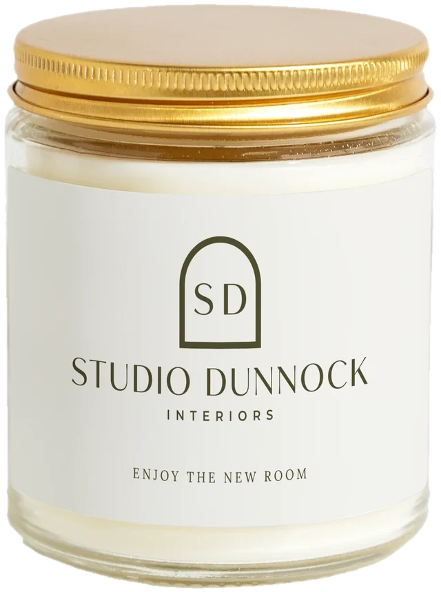A 9 oz candle jar with a sample Interior designer client gifts label
